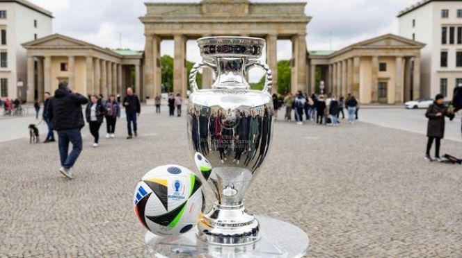 Кубок Евро-2024 и официальный мяч турнира на фоне Бранденбургских ворот в Берлине. Фото AFP