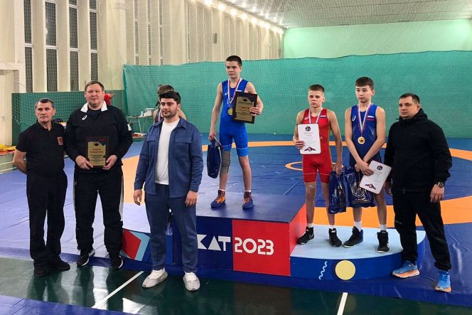 На фото Демьян Завалишин на третьей ступени пьедестала в красном борцовском трико 